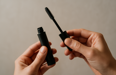 mains tenant un tube de mascara noir