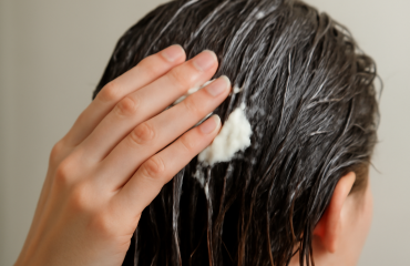 main appliquant après-shampooing sur chevelure mouillée