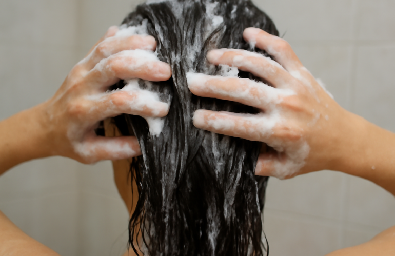 mains appliquant shampooing sur cheveux mouilles