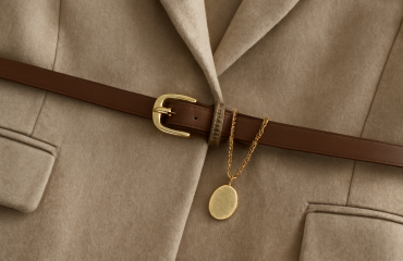 ceinture fine et bijou posé sur veste neutre