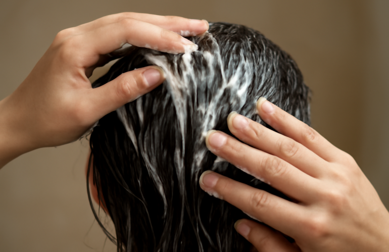 mains appliquant masque capillaire sur cheveux mouillés