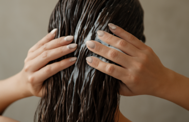 mains appliquant un masque creme sur cheveux longs